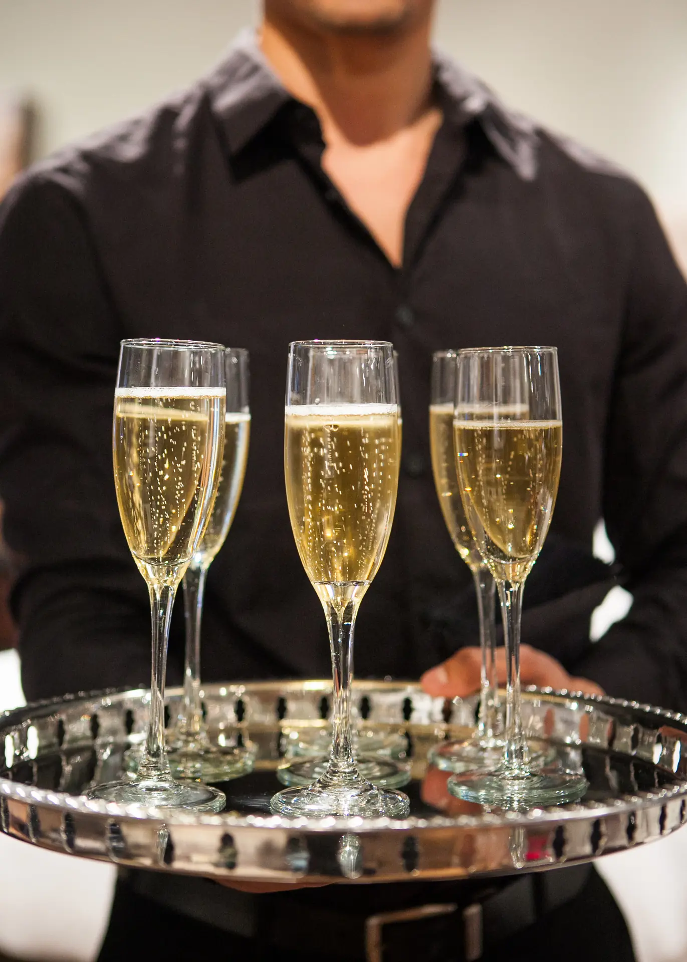 Un plateau de flûtes de crémant tenu par le serveur