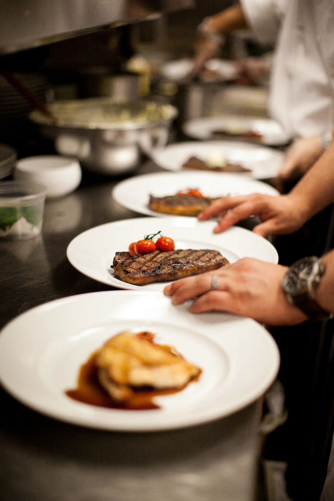 Au passe, les mains du chef posent les assiettes du service