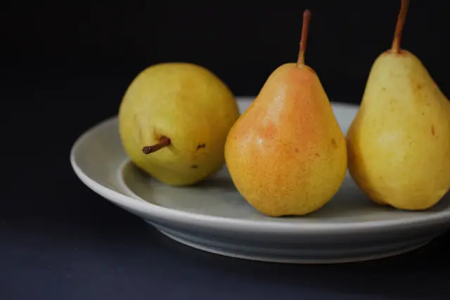 Trois poires jaunes sur une assiette grise